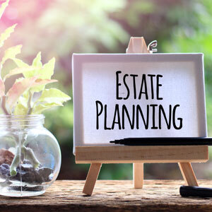 Estate planning sign on easel with pen and plant, representing legal services